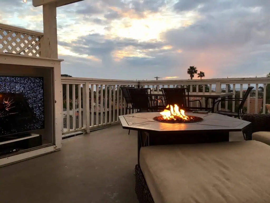 Outdoor patio with fire pit, seating, and sunset view over the neighborhood.
