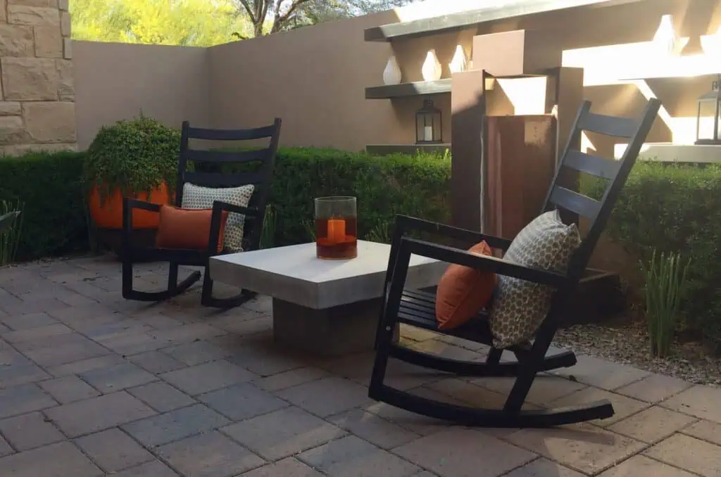 Outdoor patio with paving stones, rocking chairs, and decorative pillows.